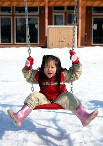 写真：大雪の中、ブランコ遊びを楽しむ柏崎凛さん＝秋堂＝。いつの時代も子どもたちは雪が大好き）