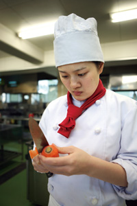 写真：おいらせ特産のニンジンの皮をむく桂奈々さん（百石高校食物調理科3年）。