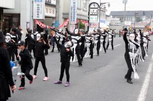 仮装行列で骸骨に扮して踊っている団体の写真です。