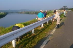 河川敷で草刈りをしている写真です。