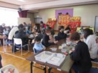 多数の親子と地域の高齢者が一緒に工作をしている様子の写真です