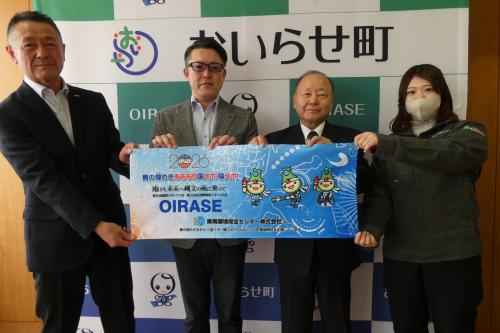 協賛品のタオルを手にする澤口取締役、佐藤正樹代表取締役、松林教育長、古内さん